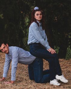 a man and woman posing for a photo in front of some trees with their hands on each other's hips