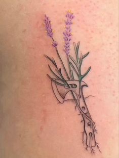 a woman's lower back tattoo with lavenders on it and scissors in the middle