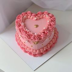 a pink heart shaped cake sitting on top of a white table