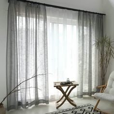 a living room with white curtains and a black and white area rug on the floor