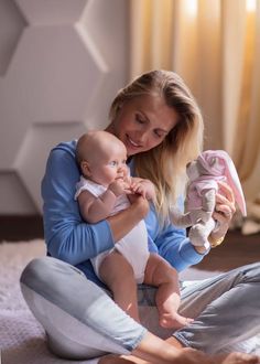 a woman sitting on the floor holding a baby