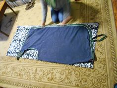 two people standing over a large piece of fabric on top of a carpeted floor