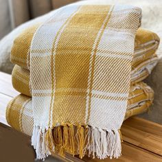 two yellow and white plaid blankets sitting on top of a wooden shelf next to a bed