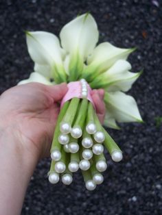 a person holding a bunch of flowers with pearls on it's end and a pink ribbon