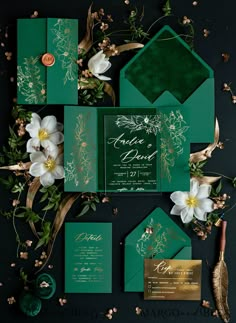 green and gold wedding stationery with white flowers on the front, dark green envelope