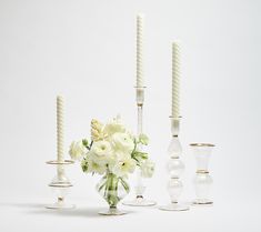 white flowers and candles are arranged in glass vases on a white tablecloth background