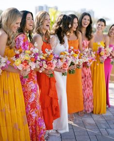 a group of women standing next to each other holding bouquets in their hands and laughing