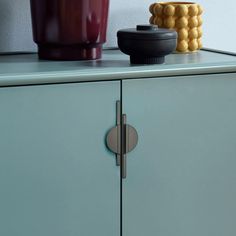 two vases sitting on top of a blue cabinet