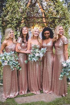 a group of women standing next to each other in front of a gazebo with greenery