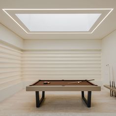 a pool table in an empty room with white walls and ceiling lights on either side