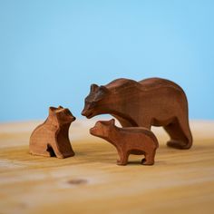 two wooden bears standing next to each other on top of a wood table with blue background