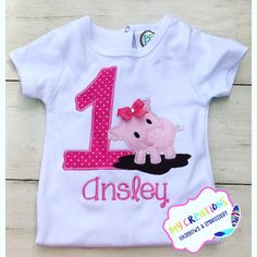 a white shirt with a pink pig on it and the number one for ansley