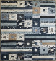 a patchwork quilt with blue and beige colors on the front, along with black and white stripes