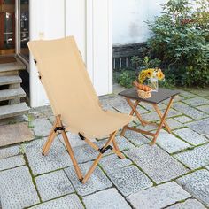 a lawn chair sitting on top of a stone floor next to a table with flowers