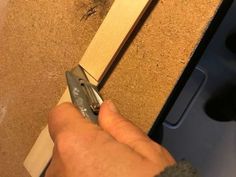 a person is using a pair of scissors to trim a piece of wood on the wall