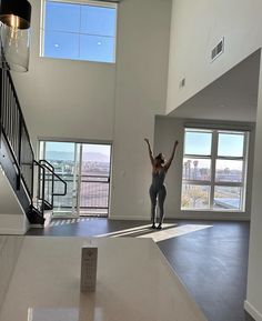 a woman standing in an empty room with her arms up