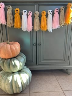 some pumpkins are stacked on top of each other in front of a gray cabinet