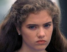 a close up of a woman with blue eyes and long hair wearing a necklace on her neck