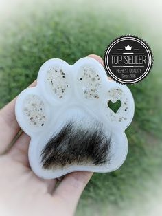 a hand holding a fake animal paw with a black moustache on it's side