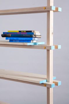 three books are stacked on top of each other in front of a gray wall with blue tape