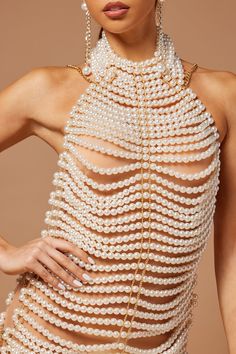 a woman with pearls on her body wearing a dress made out of pearls and chains