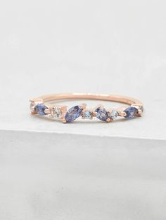 a rose gold ring with blue and white stones on the side, sitting on top of a