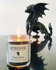 a candle sitting on top of a table next to a black dragon figurine