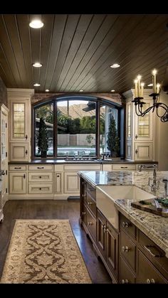 a large kitchen with white cabinets and marble counter tops, along with an area rug on the floor