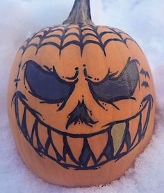 a carved pumpkin with an evil face painted on it's side in the snow