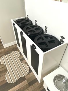 a white cabinet with three black pots in it next to a washer and dryer