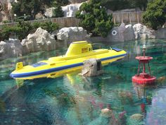 a yellow and blue boat floating on top of a body of water next to rocks