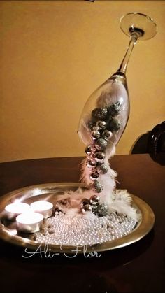 a wine glass filled with beads and candles on a tray that is sitting on a table