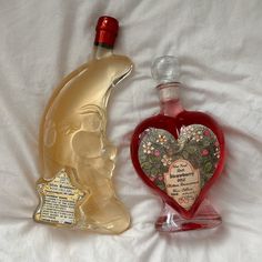 two bottles of perfume sitting on top of a white bed next to eachother