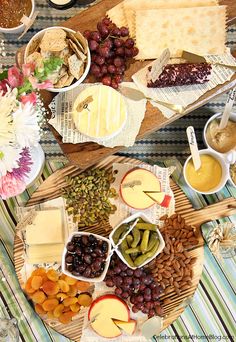 an assortment of cheeses, crackers and fruit on a table