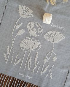 an embroidered tablecloth with flowers and leaves on it, next to a seashell