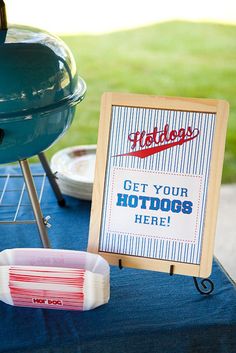 an outdoor bbq party with hotdogs on the grill and sign that says get your hot dogs here