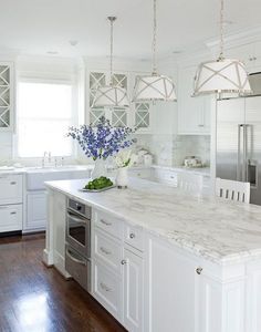 a large kitchen with white cabinets and marble counter tops, along with stainless steel appliances