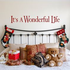 a bed with teddy bears and christmas stockings on the headboard, in front of a wall that says we love you