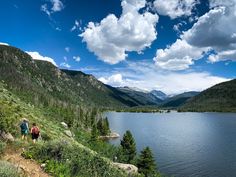 two people walking up a hill next to a lake