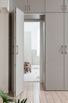 an open door leading to a bedroom with white walls and wood flooring in the foreground