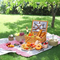 a picnic with bread, fruit and wine on a blanket in the grass under a tree