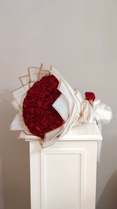 a bouquet of red roses sitting on top of a white box