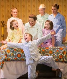 a group of people standing on top of a bed in front of a woman and two children