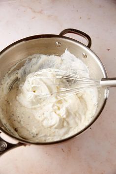 a metal bowl filled with whipped cream on top of a counter