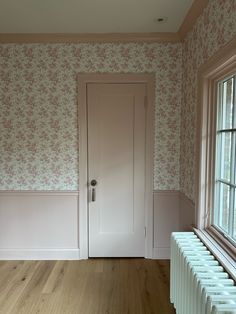 an empty room with wallpaper and a radiator in front of the door