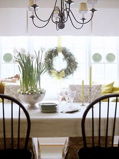 a dining room table with two chairs and a wreath on the window sill