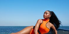 a woman in an orange swimsuit sitting on the beach