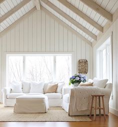 a living room with white furniture and wood flooring, along with a large window