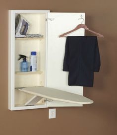 an ironing board is in the corner of a cabinet next to a towel rack