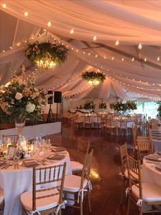 the inside of a tent with tables and chairs set up for a formal function at night